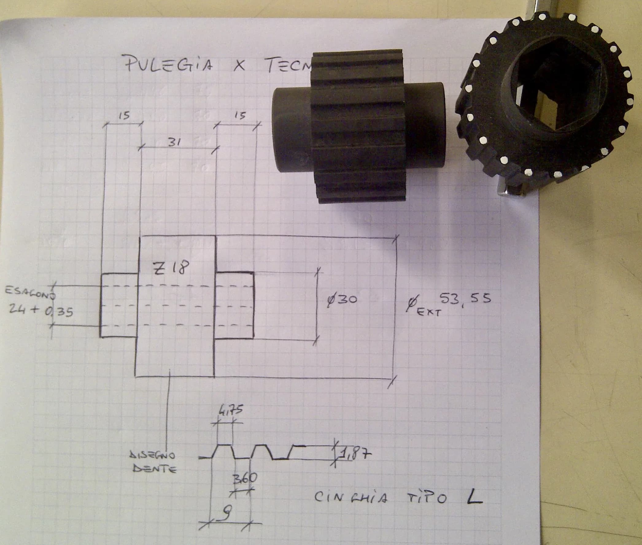 Disegno tecnico a mano di una puleggia con il pezzo realizzato appoggiato sopra