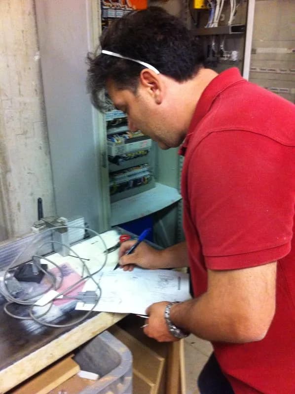 Tecnico SME compila la documentazione di un intervento davanti al quadro elettrico