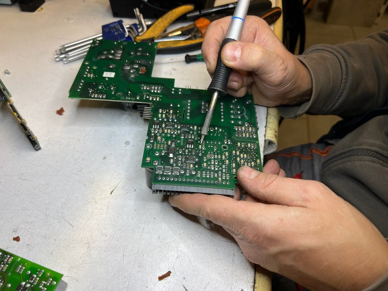 Tecnico SME al banco mentre salda una scheda elettronica industriale